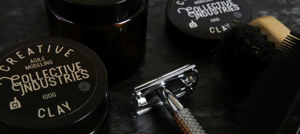Close-up of grooming products, a metal safety razor, a brush, and a comb placed on a dark surface.