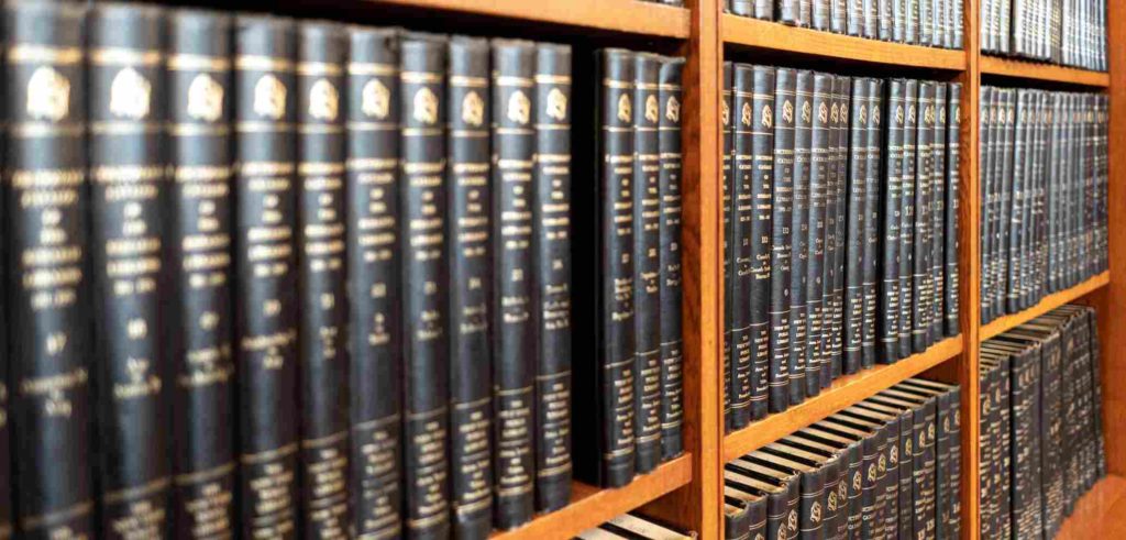 A large collection of black-bound volumes arranged on wooden bookshelves.