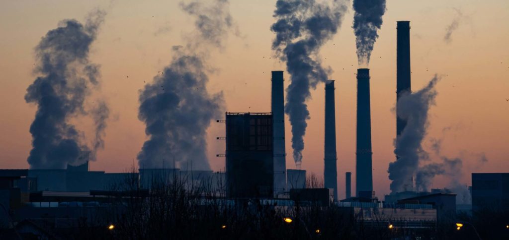 Industrial plant with multiple smokestacks emitting smoke