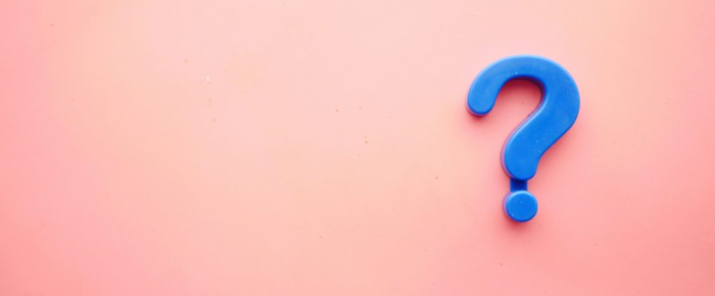 A blue plastic question mark on a pink background