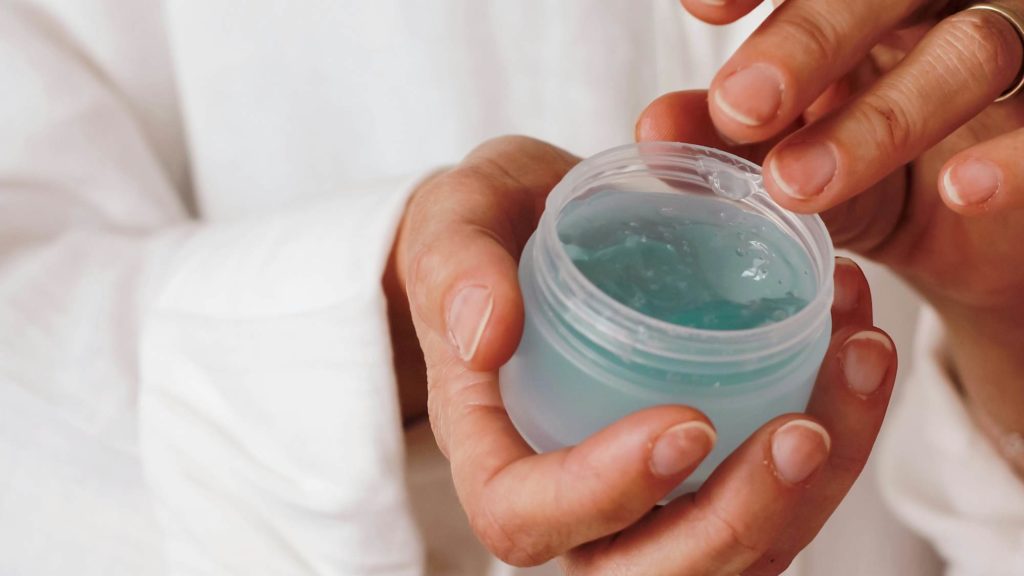 Hands holding a jar of blue gel