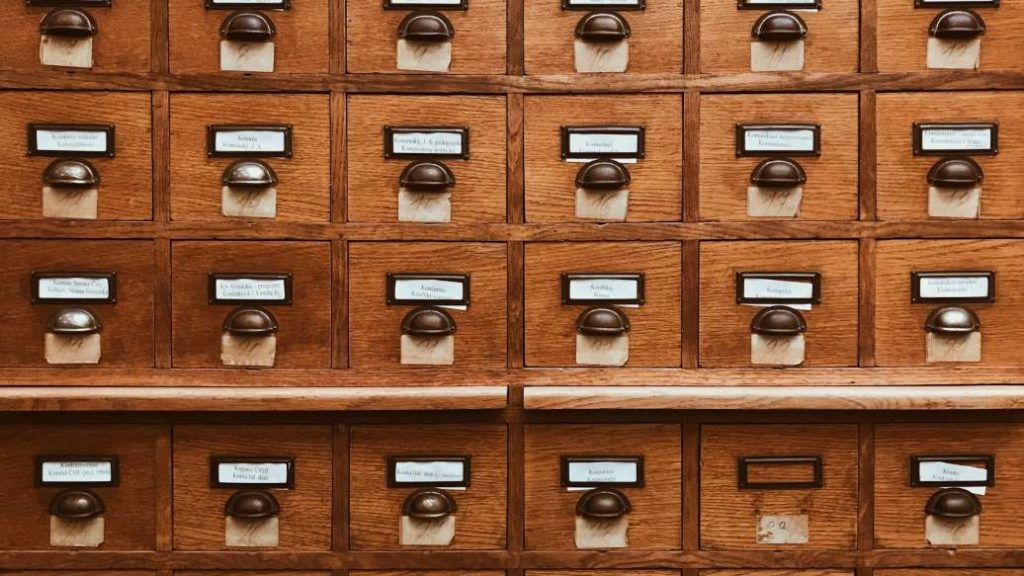 A wall of wooden filing cabinets with small drawers -cosmetovigilance in cosmetics regulations