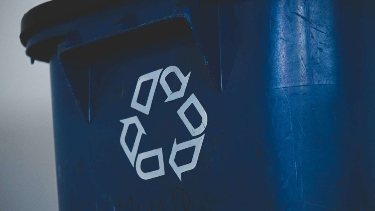 A close-up of a blue recycling bin with a white recycling symbol.