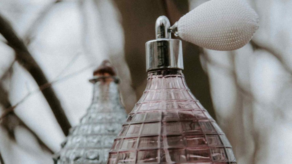 A close-up of an old-fashioned perfume bottle with a silver atomizer - challenge test in cosmetics







