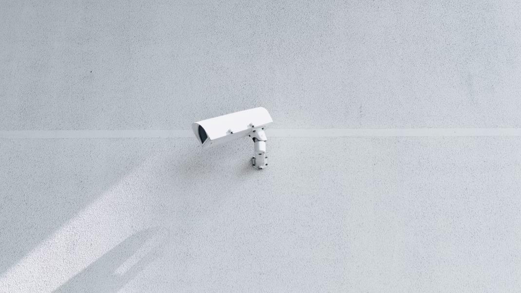 A white security camera mounted on a gray wall - cosmetovigilance in cosmetics regulations