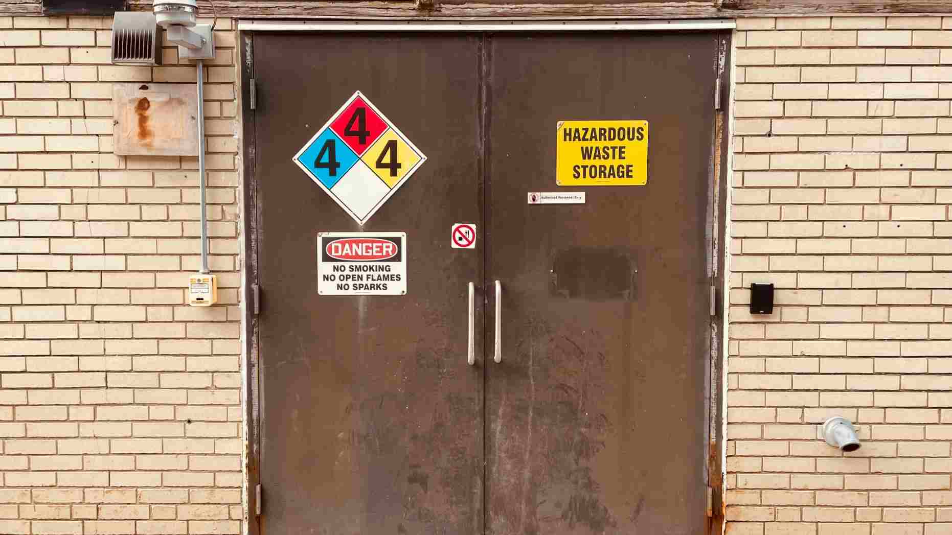 A pair of metal double doors with "Hazardous Waste Storage" signs - Classification Labelling Packaging Chemicals (CLP)