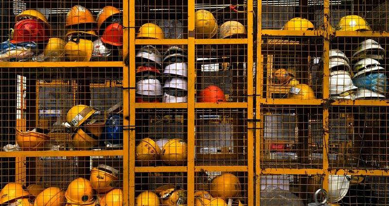 a group of yellow and white helmets in a cage-general product safety regulation