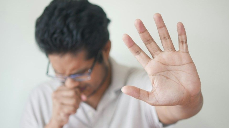 man coughing with one hand hold out