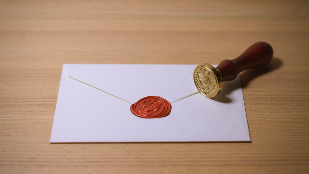 an envelope sealed with a branded red wax on a wooden table