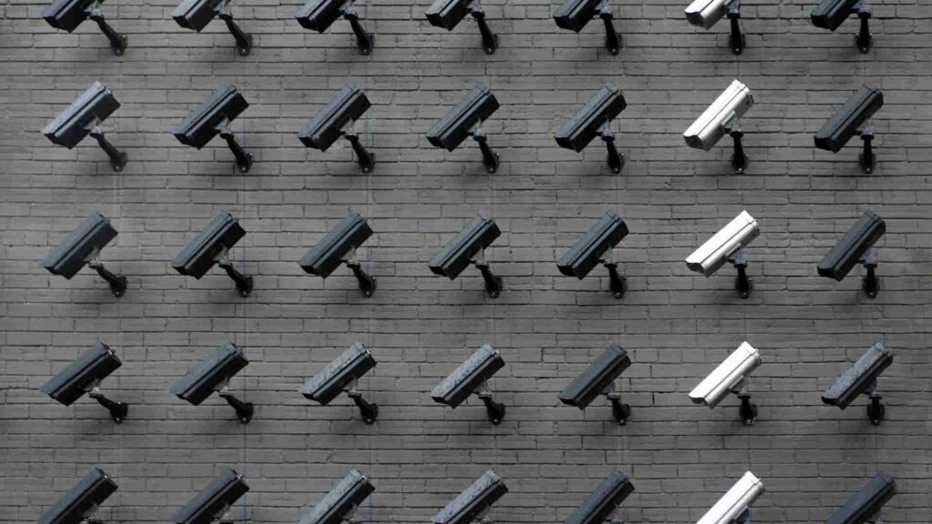 several rows of surveillance cameras on a grey wall
